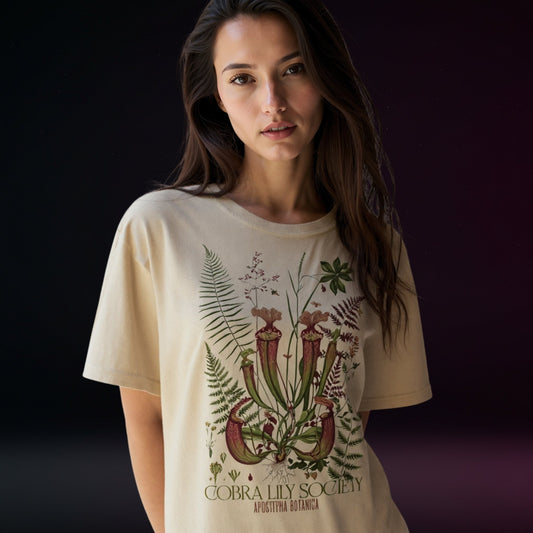 Woman wearing a beige t-shirt with botanical design and text on a dark background