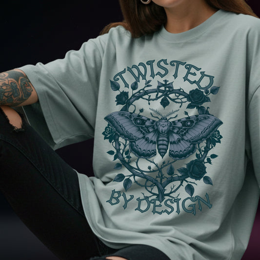 Light blue t-shirt with moth design and 'Twisted by Design' text worn by a person.