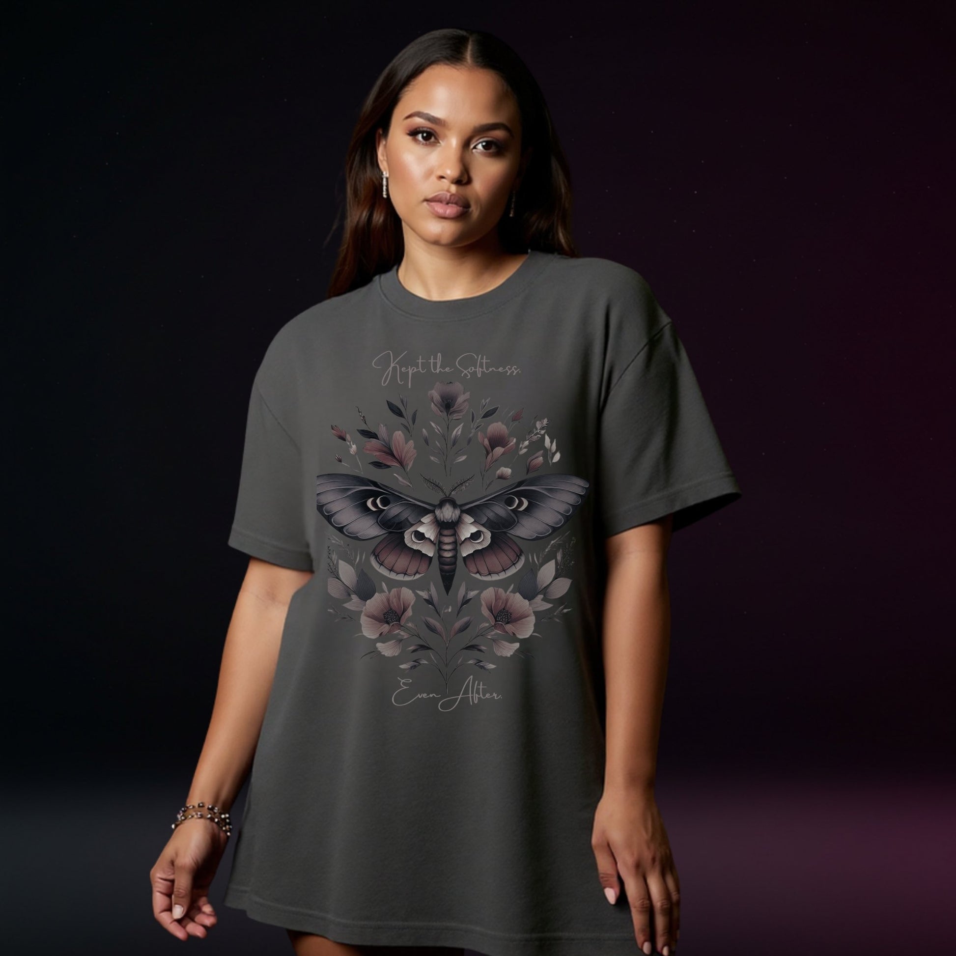 Woman wearing a dark gray t-shirt with a moth and floral design on a dark background