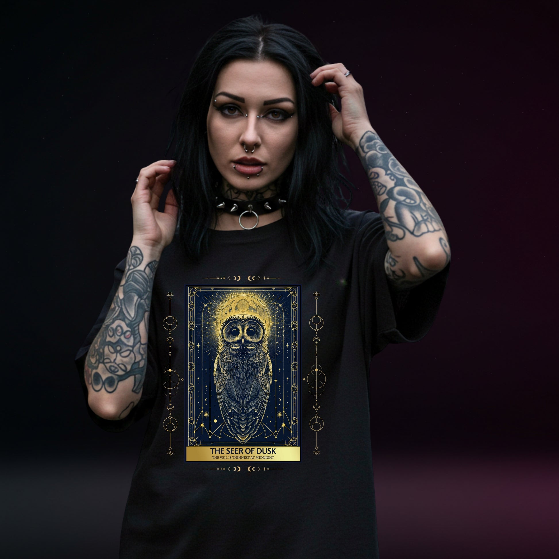Woman wearing a black t-shirt with a tarot card owl design and text on a dark background